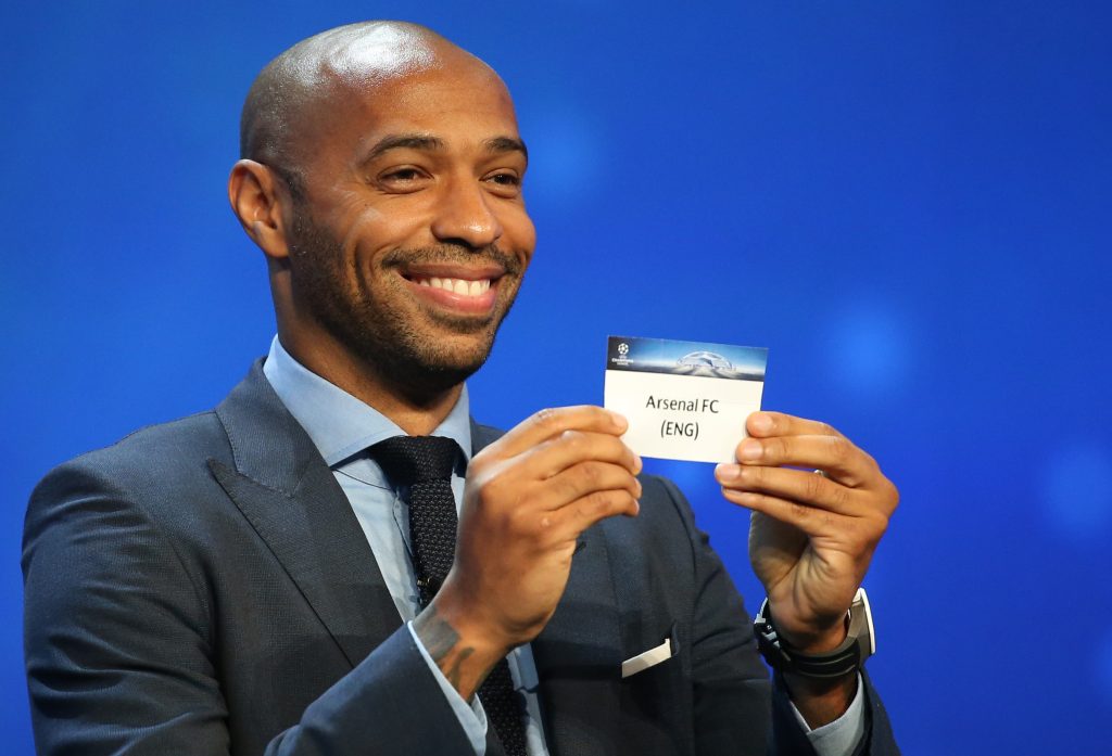 Thierry Henry holds a paper with the name of Arsenal.