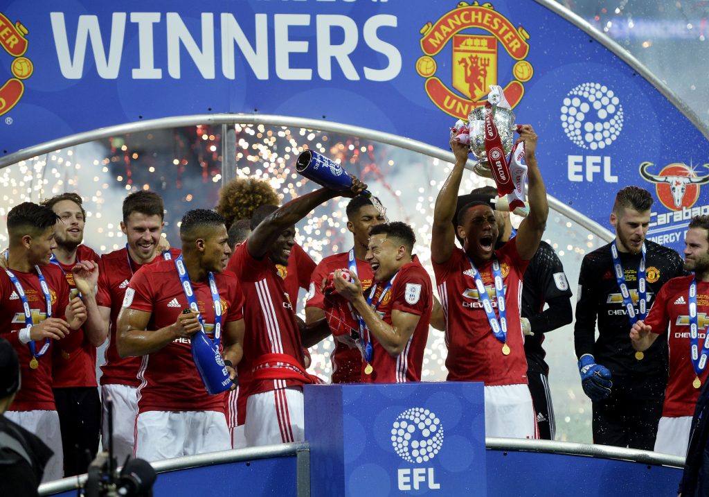 Manchester United's Eric Bailly pours champagne over Jesse Lingard as they celebrate with team mates and trophy after winning the EFL Cup Final.
