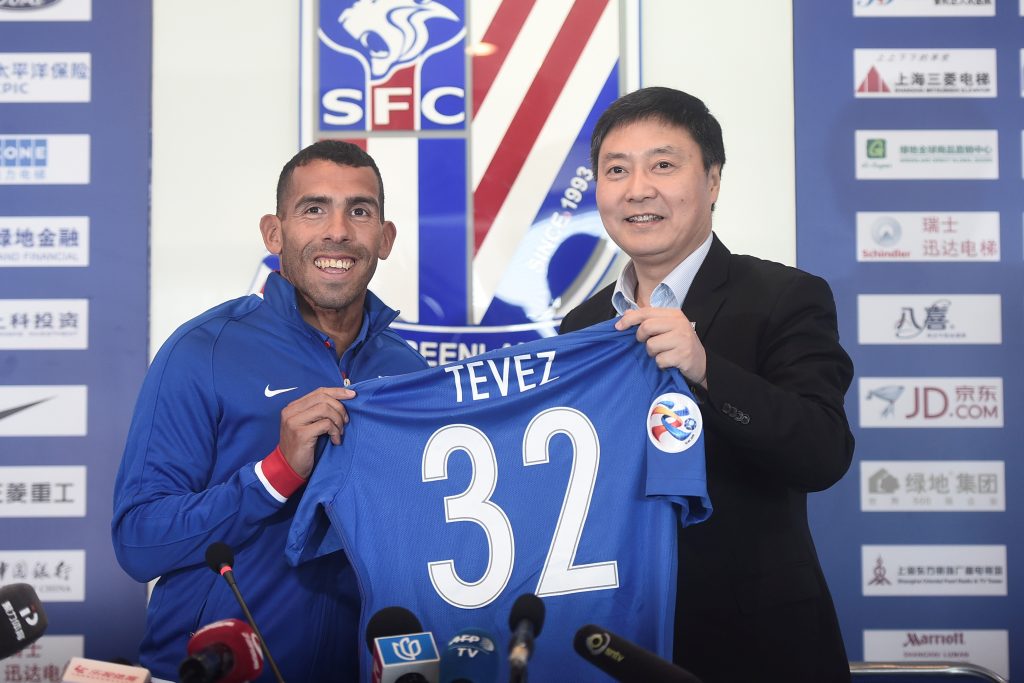 Carlos Tevez holds a team shirt with Wu Xiaohui, Chairman of Shanghai Greenland Shenhua Football Club.
