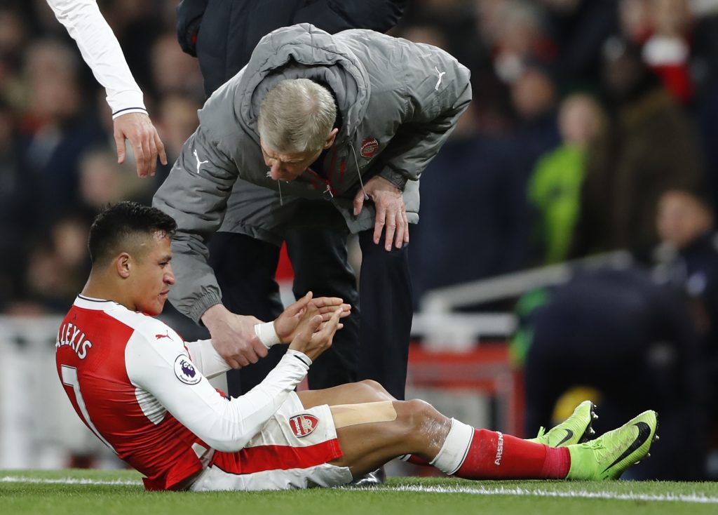 Arsenal manager Arsene Wenger speaks with Alexis Sanchez as he sits injured.