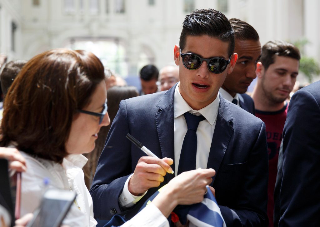 Real Madrid's James Rodriguez signs an autograph during a ceremony.