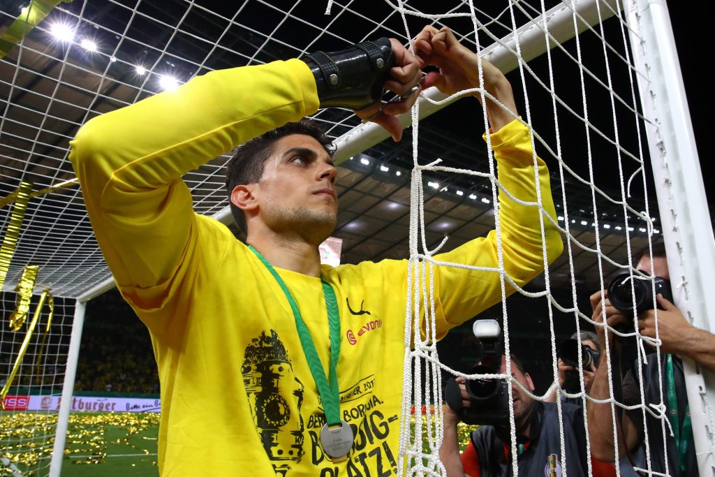 Borussia Dortmund's Marc Bartra cuts the net with a pair of scissors as he celebrates after victory.
