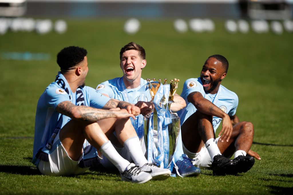 Man City's John Stones, Kyle Walker and Raheem Sterling celebrate with the trophy after winning the Premier League title.