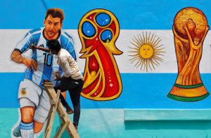 A painter applies finishing touches to an image of Argentina's soccer player Lionel Messi, on a wall along a road ahead of the FIFA World Cup.