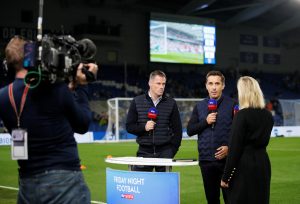 Jamie Carragher and Gary Neville performing media duties beside the pitch before the match.