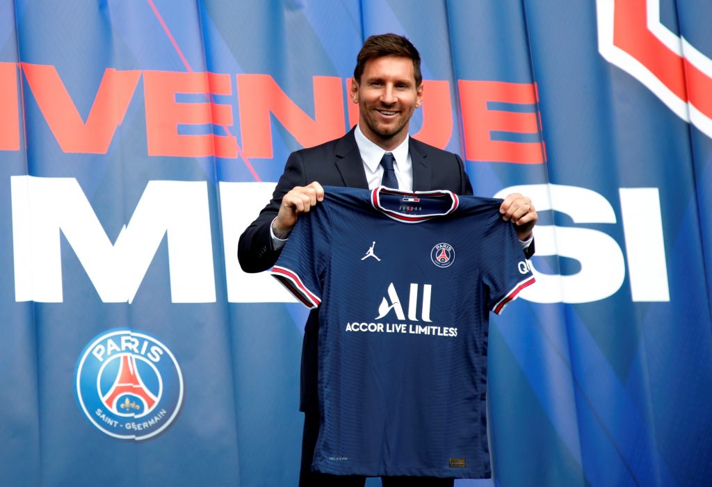 Paris Saint Germain's Lionel Messi poses with a shirt on the pitch after the press conference.